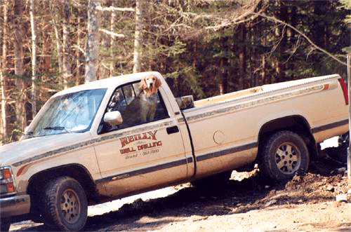 Reilly Well Drilling white pickup truck in a Maine forest